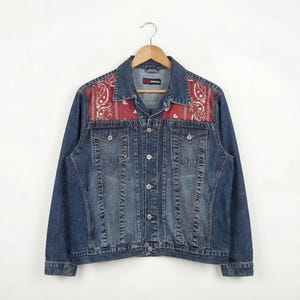 Può includere: Giacca di jeans blu con tessuto rosso a fantasia paisley sulle spalle. La giacca ha una chiusura con bottoni, due tasche sul petto e due tasche laterali. L'etichetta del marchio Diesel è visibile.