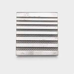 May include: A rectangular silver-colored metal plate featuring a series of seven horizontal, parallel grooves. Each groove displays a distinct rope-like or twisted texture, varying in thickness and detail across the surface of the metal block.