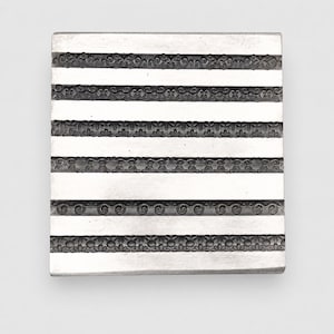 May include: A square silver-toned metal plate featuring five horizontal bands of intricate embossed patterns. The design includes alternating smooth flat strips and detailed decorative borders with floral, scroll, and geometric motifs.