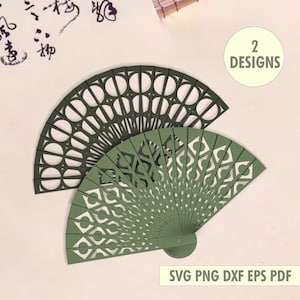 Op de afbeelding: Twee decoratieve papieren waaiers in groen- en donkergroentinten, met ingewikkelde uitgesneden ontwerpen. Eén waaier is over de andere geplaatst. De afbeelding bevat de tekst "2 DESIGNS" en "SVG PNG DXF EPS PDF".