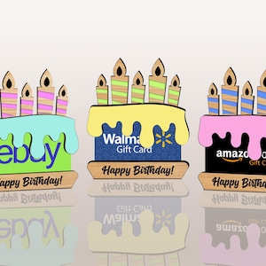 Könnte beinhalten: Drei hölzerne Geburtstagskuchendekorationen mit farbenfrohem Zuckerguss und Kerzen. Jeder Kuchen zeigt ein anderes Logo: eBay, Walmart und Amazon. Der Text "Happy Birthday!" ist auf jedem Kuchen zu sehen.