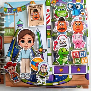 Peut inclure: Un cahier d'activités à spirales avec des autocollants colorés de personnages du film d'animation Toy Story. Les autocollants incluent Woody, Buzz l'Éclair, M. Patate et d'autres. Le fond représente une scène de chambre avec une affiche « Wanted ».