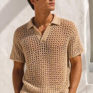 May include: A beige short-sleeved polo shirt featuring an open-knit crochet construction with a textured grid pattern, a classic collar, and a V-neck placket, paired with light-colored drawstring trousers and dark-framed sunglasses.