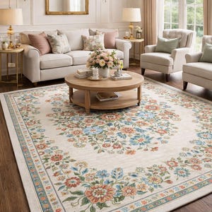 Puede incluir: Una alfombra de área crema con un estampado floral en tonos azules, naranjas y verdes. La alfombra está en un salón con un sofá, sillas y una mesa de centro. La alfombra mide aproximadamente 244 x 305 cm.