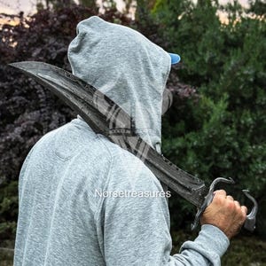 May include: A curved Damascus steel sword with a distinct wavy pattern on the blade, featuring a metal hilt with a curved guard and pommel. The sword is held over the shoulder, showcasing the dark, layered metal texture and sharp edge.