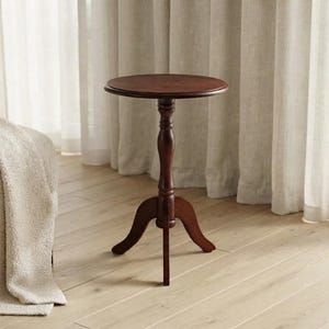 May include: A dark brown wooden side table featuring a smooth circular top surface, a central turned pedestal column, and three curved legs that extend outward to provide a stable base for the furniture piece in a standing position.