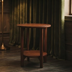 May include: A round wooden side table featuring a smooth, circular top and a lower shelf supported by four curved legs. The table is constructed from a medium-toned brown wood with a visible grain, showcasing a simple, functional design.