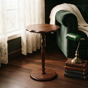May include: A dark brown wooden side table with a scalloped circular top and a single pedestal base. The table features a smooth, polished finish and a central turned column that connects the tabletop to a sturdy, flat circular base on the floor.