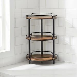 May include: A three-tiered corner shelf with a black metal frame and wooden shelves. The shelves are round and have a raised metal edge. The shelf is placed in a corner against a white tiled wall.