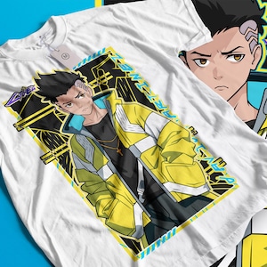 Pode incluir: Camiseta branca com um personagem de estilo anime usando uma jaqueta amarela e preta. O design inclui o texto "ARTIME" e formas geom&eacute;tricas. O personagem tem cabelo preto e um pingente de cruz. Outra camiseta &eacute; parcialmente vis&iacute;vel.