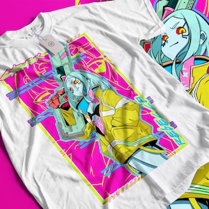 Op de afbeelding: Wit t-shirt met een levendig grafisch ontwerp. Het ontwerp toont een futuristisch anime-achtig personage met blauw haar, een gele jas en een wapen, tegen een roze en blauwe geometrische achtergrond. Het woord "REBEL" is zichtbaar.