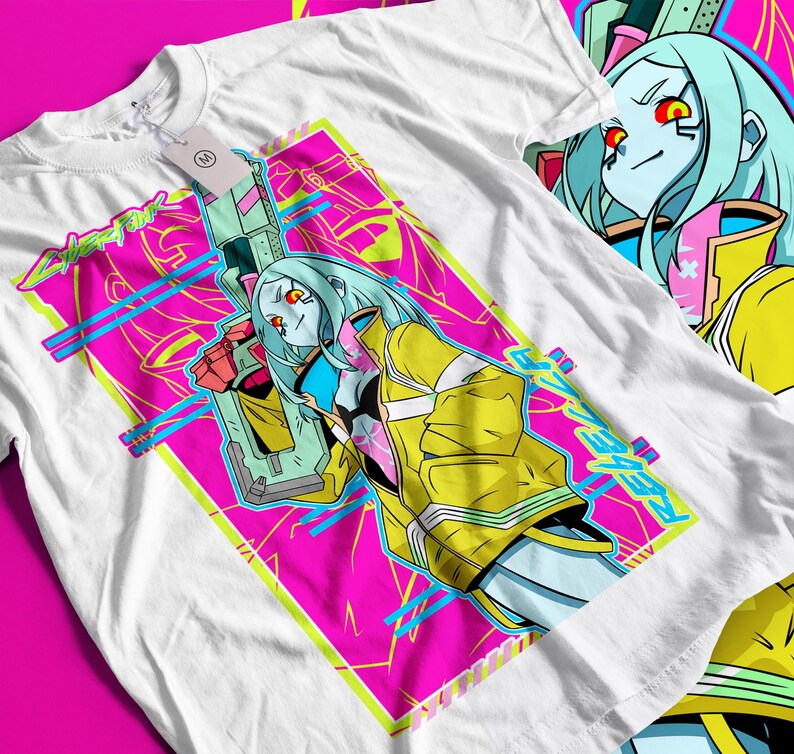 Op de afbeelding: Wit t-shirt met een levendig grafisch ontwerp. Het ontwerp toont een futuristisch anime-achtig personage met blauw haar, een gele jas en een wapen, tegen een roze en blauwe geometrische achtergrond. Het woord "REBEL" is zichtbaar.