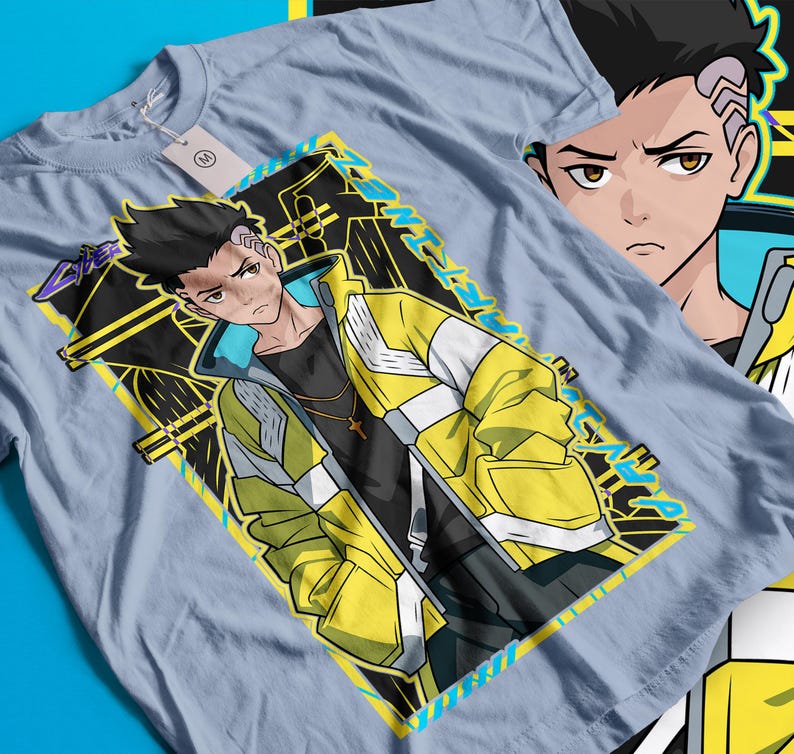 Pode incluir: Camiseta azul clara com um personagem de estilo anime usando uma jaqueta amarela e branca. O design inclui o rosto do personagem e um padr&atilde;o geom&eacute;trico com texto. Uma etiqueta est&aacute; presa &agrave; camiseta.