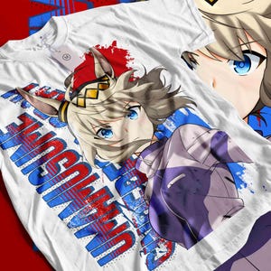 May include: White t-shirt with a vibrant anime-style illustration of a character with blue eyes and light brown hair. The shirt features the word "UNSUN" in red and blue block letters. The design includes red and blue paint splatters.