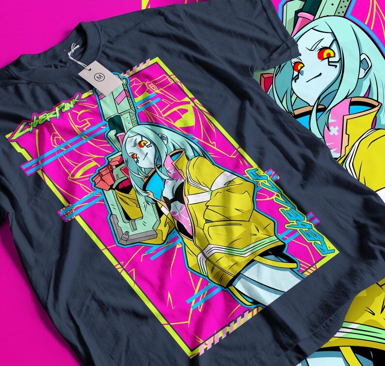 Op de afbeelding: Donker marineblauw T-shirt met een levendig grafisch ontwerp. Het ontwerp bevat een personage met blauw haar, een gele jas en een wapen, tegen een roze en gele achtergrond. Het woord "Cyberpunk" is zichtbaar in het ontwerp.