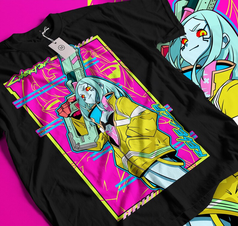 Op de afbeelding: Zwart t-shirt met een levendig grafisch ontwerp. Het ontwerp toont een personage met blauw haar, een gele jas en een wapen, tegen een roze en blauwe achtergrond. Het woord "CYBERPUNK" is ook zichtbaar.