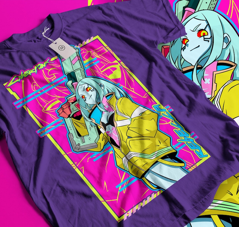 Op de afbeelding: Paars T-shirt met een opvallende grafische afbeelding. Het ontwerp toont een personage met blauw haar, een gele jas en een wapen, tegen een roze en gele achtergrond. Het woord "Cyberpunk" is ook zichtbaar.