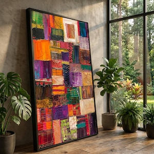 May include: A framed abstract painting with a patchwork design. The artwork features a vibrant mix of colors including orange, purple, green, and red. The painting is leaning against a concrete wall near a window with plants.