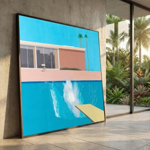 May include: Framed art print showing a swimming pool scene. The artwork features a bright blue pool with a yellow diving board and a splash of water. A mid-century modern style building is in the background, under a clear blue sky. Palm trees are also visible.
