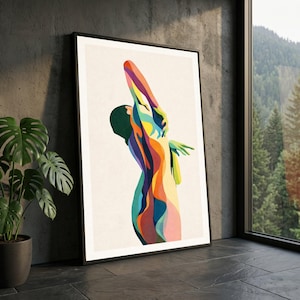 Puede incluir: Una impresión artística enmarcada que presenta una figura abstracta colorida con los brazos extendidos. La obra de arte utiliza una paleta de colores vibrantes que incluyen amarillo, naranja, azul y verde. La impresión se muestra en un marco negro sobre un fondo neutro.