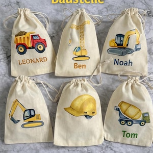Peut inclure: Six sacs en tissu écru à cordon de serrage ornés d'illustrations sur le thème de la construction, notamment un camion-benne, une grue, une pelleteuse, un casque de chantier et une bétonnière, personnalisés avec les prénoms Leonard, Ben, Noah et Tom.
