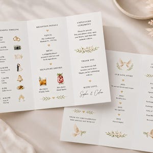 May include: A tri-fold wedding programme printed on white cardstock with black serif text and watercolour illustrations. The layout includes a wedding timeline, reception details, an unplugged ceremony request, an order of ceremony, and love story.