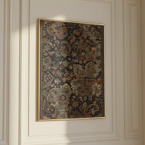 May include: A rectangular wall art piece featuring a dark, intricate floral and paisley pattern in shades of black, deep red, muted green, and gold, encased in a thin, metallic gold frame that highlights the detailed, tapestry-like design.