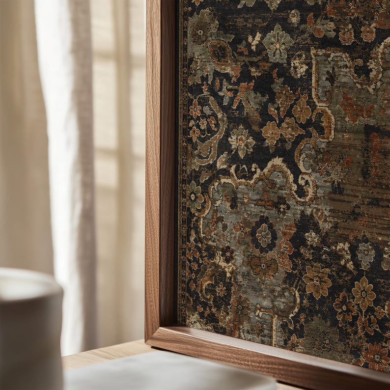May include: A framed wall art piece featuring a dark, intricate floral and damask pattern in shades of black, muted green, and burnt orange. The artwork is encased in a smooth, medium-toned wooden frame with a visible grain, set vertically.