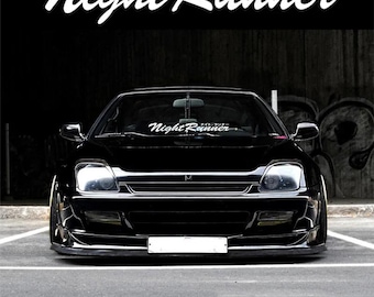Könnte beinhalten: Ein schwarzes Sportauto mit dem Text "Night Runner" in weißer Schrift oben und auf der Windschutzscheibe. Das Auto parkt auf einer grauen Oberfläche mit dunklem Hintergrund. Das Auto hat ein niedriges Profil und einen Frontspoiler.