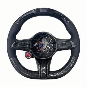 以下が含まれることがあります： 赤色の「START STOP」ボタンが付いた、黒とカーボンファイバーのステアリングホイール。ハンドルには、穴あきレザーグリップと統合されたコントロールが付いています。中央には露出した配線と小さなディスプレイ画面があります。