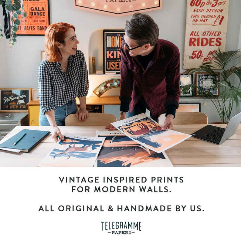 May include: Two people are looking at vintage-inspired prints on a table. The prints feature colorful illustrations of animals and landscapes. The text on the prints reads "SCOTLAND", "DISTRICT", and "INVERNESS". The text on the sign above the table reads "TELEGRAMME -PAPER-".