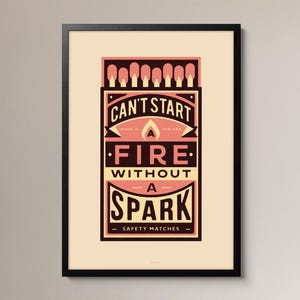 May include: A framed rectangular print featuring a graphic illustration of a matchbox with a row of matches at the top. The text reads CAN'T START A FIRE WITHOUT A SPARK, MADE IN THE USA, and SAFETY MATCHES in black, cream, and salmon pink colors.