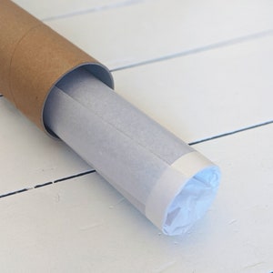 May include: A rolled up print or poster is wrapped in white tissue paper and secured in a brown cardboard tube.