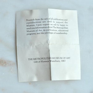May include: A folded, off-white paper with printed text from The Metropolitan Museum of Art. The text includes information about publications, educational programs, and membership privileges. The paper is a gift from Florence Waterbury, 1967.