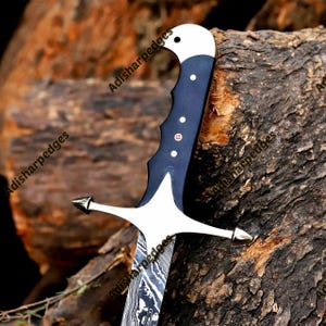 Pode incluir: Uma faca de l&acirc;mina fixa com uma l&acirc;mina de a&ccedil;o Damasco com padr&atilde;o ondulado, um cabo azul escuro com pinos prateados e uma guarda prateada. O texto Adisharpedges &eacute; vis&iacute;vel na imagem. O cabo tem um pomo curvo.