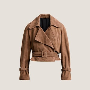 May include: A brown suede jacket with a wide collar, a belted waist, and buttoned cuffs. The jacket has a double-breasted design and a tailored fit. The jacket is a neutral color and is suitable for various occasions.