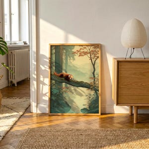 May include: A framed art print featuring a red panda resting on a tree branch in a forest scene. The artwork has a warm color palette with shades of green, brown, and orange. The print is displayed in a room with natural light.