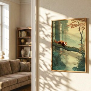 May include: A framed art print depicts a red panda resting on a tree branch in a forest scene. The artwork features a serene landscape with a river, trees, and a soft, warm color palette. The frame is a light brown color.