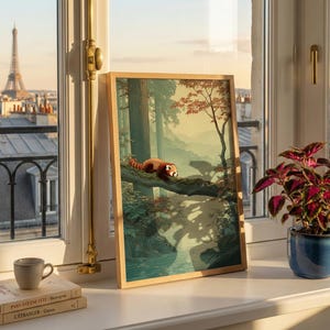 May include: A framed art print featuring a red panda resting on a tree branch in a forest scene. The print is displayed on a windowsill with a view of the Eiffel Tower and Parisian rooftops. A small potted plant and a stack of books are also on the windowsill.