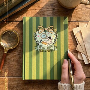 May include: A green and yellow striped notebook with the words "Mystery Book Club" on the cover. A magnifying glass, a cup of tea, and a stack of books are on a wooden surface.