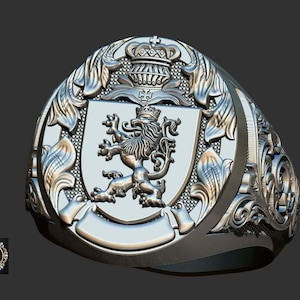 May include: A silver ring with an elaborate design. The ring showcases a shield with a lion emblem, a crown, and decorative scrollwork. The ring has a wide band and a detailed, textured surface.