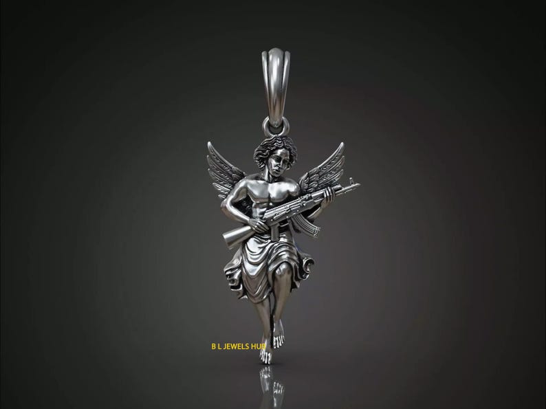 Puede incluir: Colgante de plata que representa un &aacute;ngel alado sosteniendo un rifle de asalto. El &aacute;ngel est&aacute; representado en un estilo cl&aacute;sico, con alas detalladas y t&uacute;nicas fluidas. El colgante tiene un lazo para una cadena.