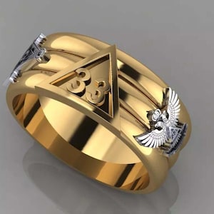 May include: A gold-colored ring with a prominent design. The ring features a triangle with the number "33" inside, flanked by detailed silver-colored eagle and other decorative elements. The ring has a polished finish.