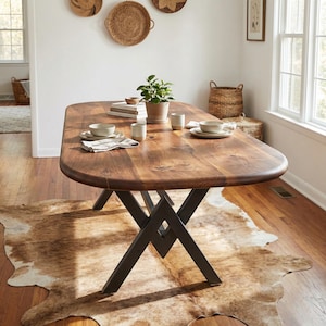 May include: A large, oval-shaped wooden dining table with a dark brown finish. The table has black metal legs and is set with dishes, cups, and a small potted plant. A cowhide rug is beneath the table.