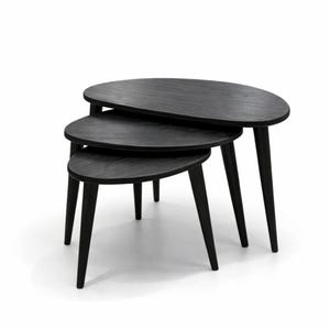 Puede incluir: Juego de tres mesas nido negras con tapas ovaladas y patas cónicas. Las mesas son de madera y tienen un diseño minimalista. La mesa más grande mide aproximadamente 76 cm de largo. Diseño moderno.