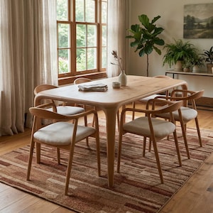 May include: A wooden dining table and six chairs in a light wood finish. The chairs have curved backs and cream-colored seats. The table sits on a patterned rug with brown and beige tones. The room features large windows and neutral curtains.