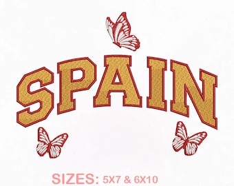 May include: An embroidery design featuring the word SPAIN in gold block letters with a red outline, arched across the center. Three white and red butterflies are positioned around the text. Text at the bottom reads SIZES: 5X7 & 6X10, PES, DST, EXP, JEF, VP3.