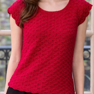 May include: A red crochet top with a round neckline and short sleeves. The top has a textured pattern and is shown on a person. The text "Easy To Follow Crochet Pattern" is at the bottom of the image.