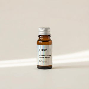 May include: A small, brown glass bottle with a silver cap. The label reads "KIRKE FRAGRANCE OIL FOR PERFUME MAKING 10 ML DOSAGE %20". The bottle is filled with a clear liquid and sits against a neutral background.