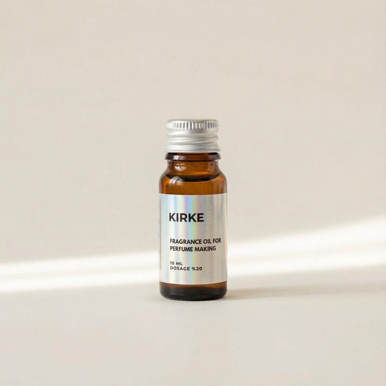 May include: A small, brown glass bottle with a silver cap. The label reads "KIRKE FRAGRANCE OIL FOR PERFUME MAKING 10 ML DOSAGE %20". The bottle is filled with a clear liquid and sits against a neutral background.